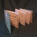 An accordion folded book with words from the Bible.