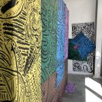 Large-scale black line drawings on colorful paper hanging on the gallery walls.