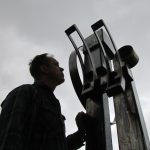 Black and white photo of man with large metal sculpture