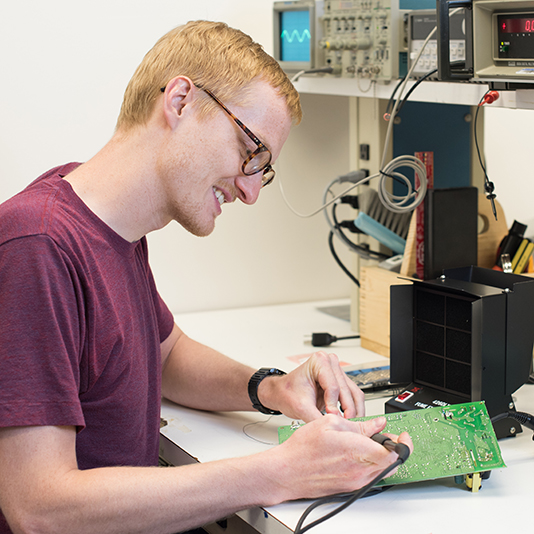 Student working on a circuit board in class