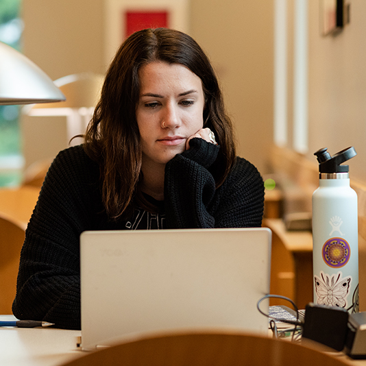 Student working on a laptop on campus