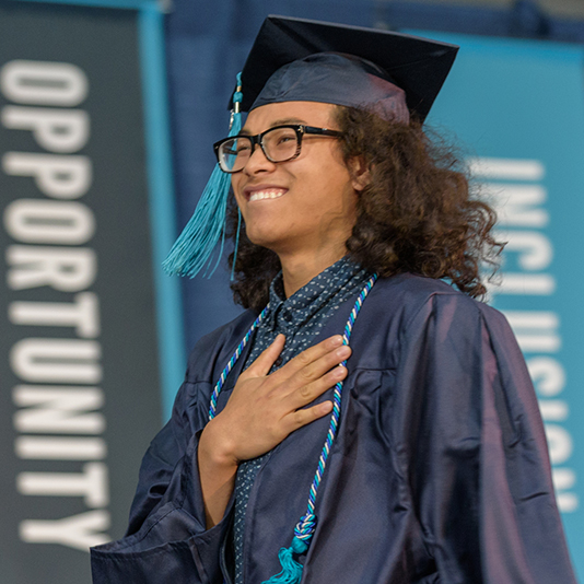 Student at PCC graduation smiling on stage after getting their diploma