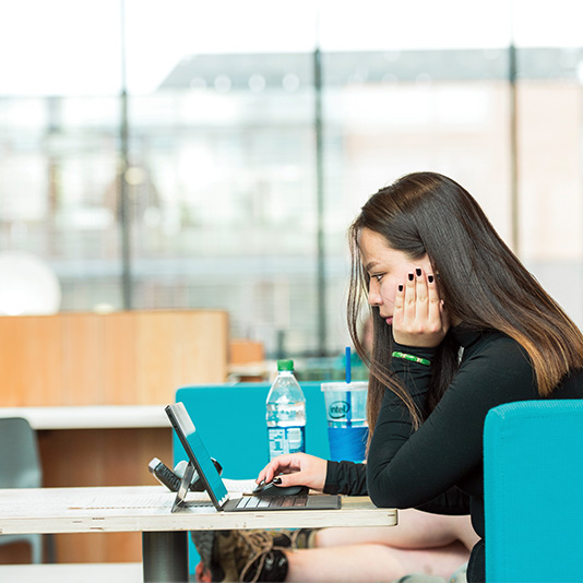 Student studying in a common area on campus