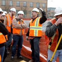 Derrick Beneville, project manager for Hoffman, discusses with the PCC students the kinds of jobs that are on the Cascade construction site. On the right, surveyor Darryl Ming of Ming Surveyors, Inc., scopes out the area.