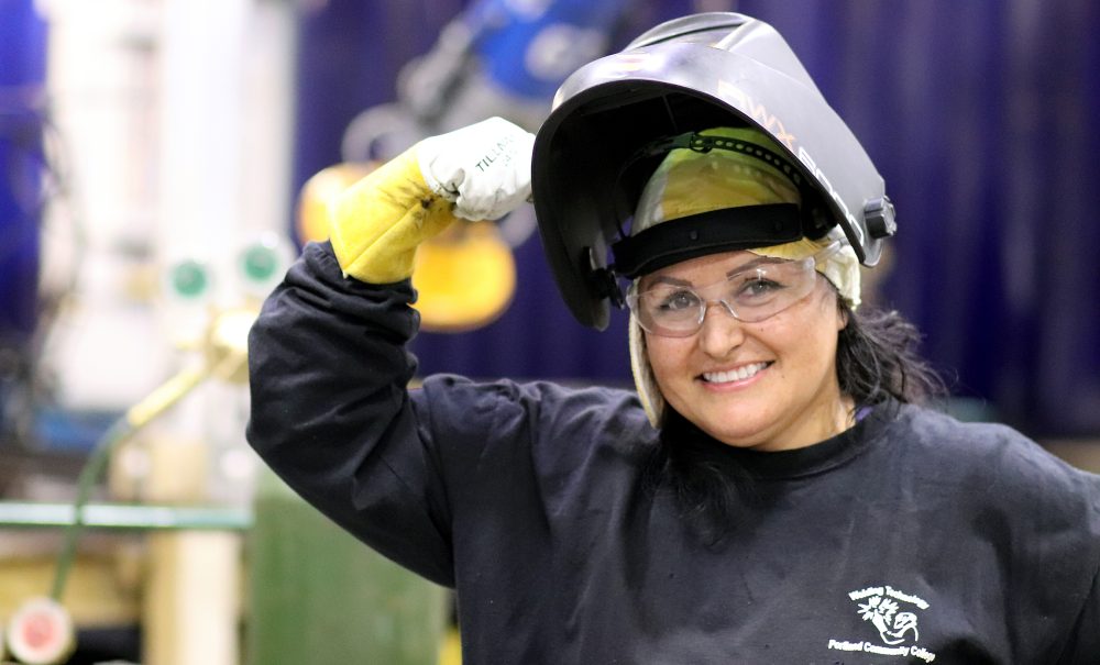 Juanita flexes in welding garb