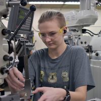 Kennedy Godfrey working a CNC in Sylvania machining shop.