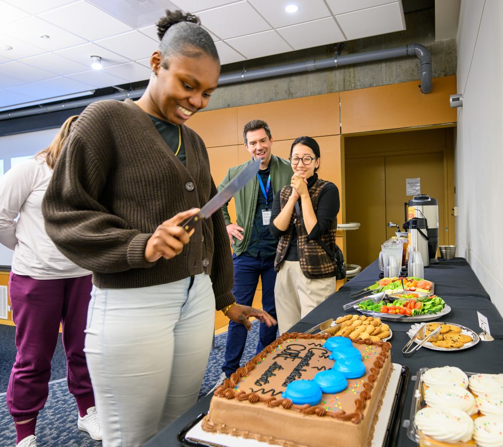 Demoriauna Jacobs readies to cut the cake symbolizing her cohort's graduation.