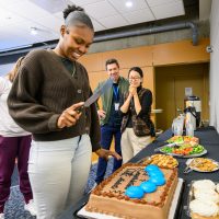 Demoriauna Jacobs readies to cut the cake symbolizing her cohort's graduation.