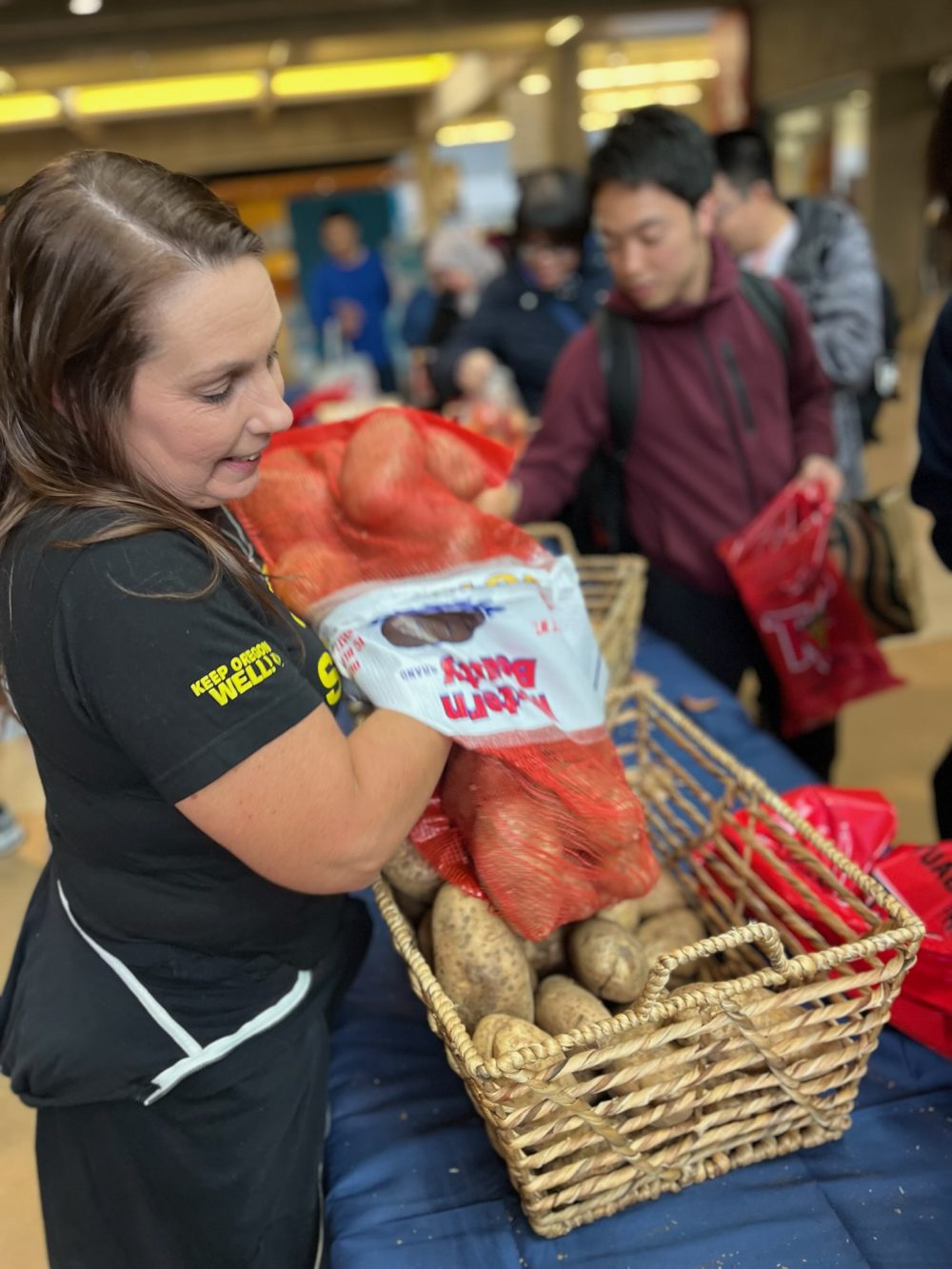 Photo of a staff member setting up a basket of potatoes at a free food market