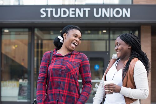 Student leaders laugh together in front of the Student Union building