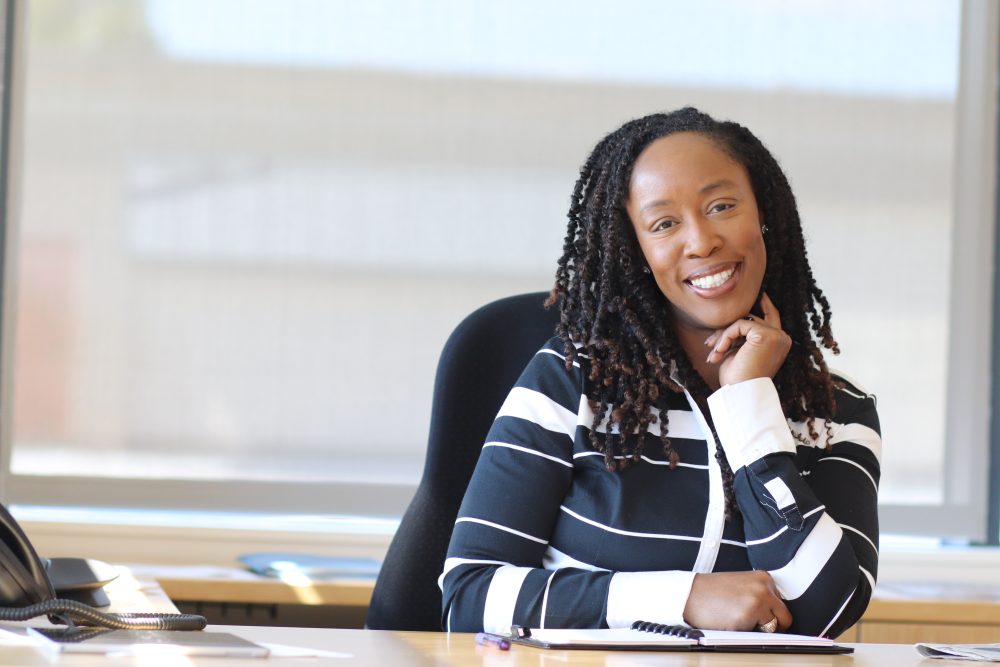 Dr. Adrien Bennings at her desk and smiling at the camera