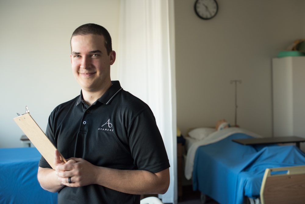 Health care professional Nick Minch standing with clipboard in hospital room