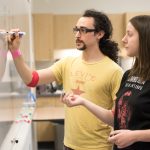 Two students write what they have learned on whiteboard in CLIMB classroom