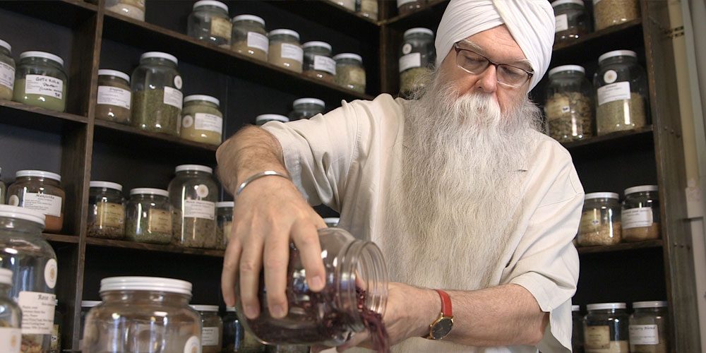 Instructor KP Khalsa stands in herbalism storeroom