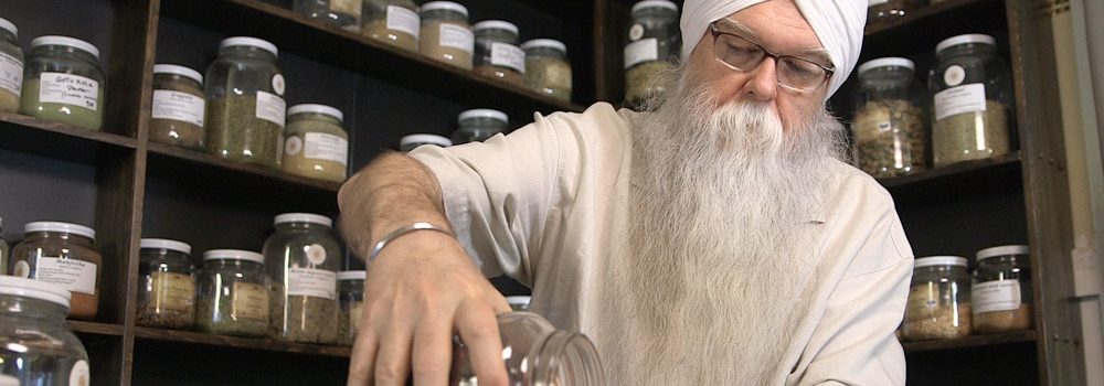 Instructor KP Khalsa stands in herbalism storeroom