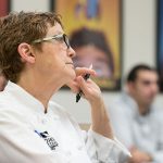 Woman in white chef uniform sitting in PCC CLIMB classroom