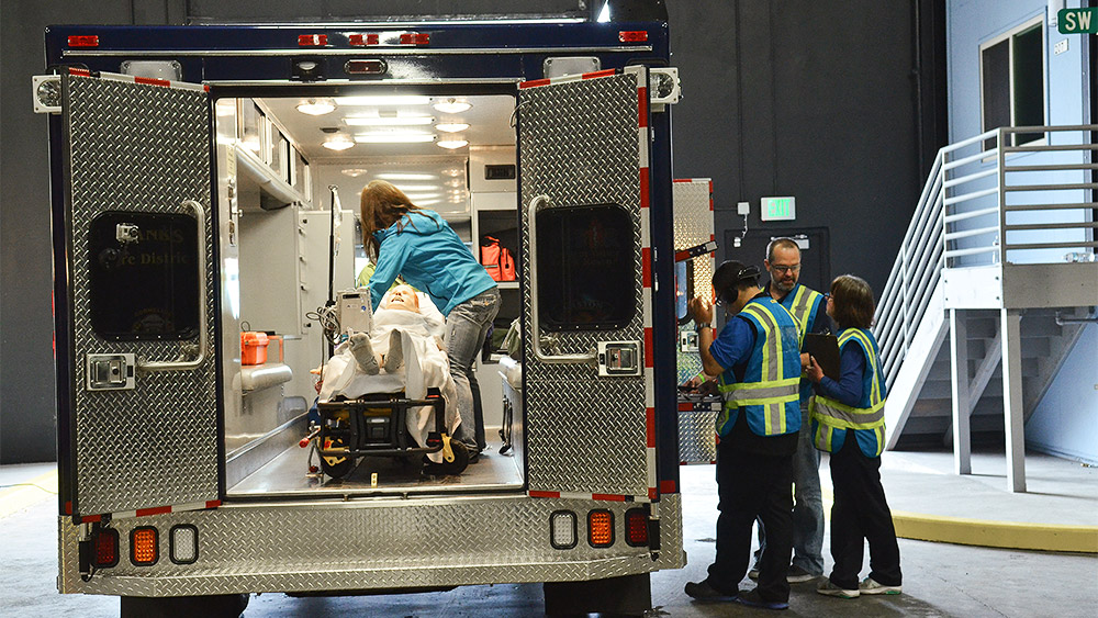 Students putting a dummy into an ambulance in a simulation