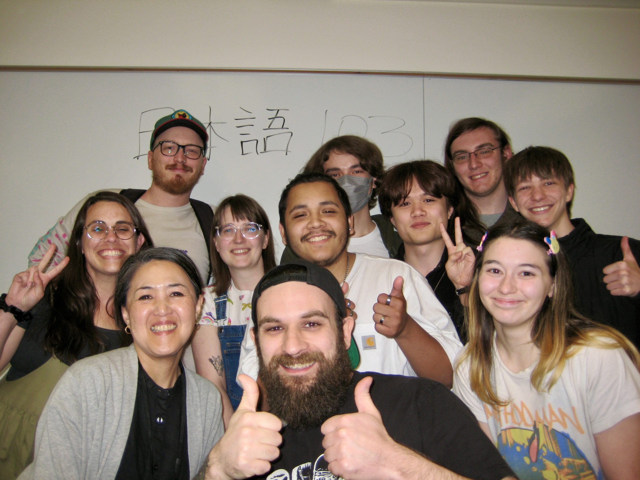 JPN 103 Students and Yumiko Omata posing in front of a classroom whiteboard